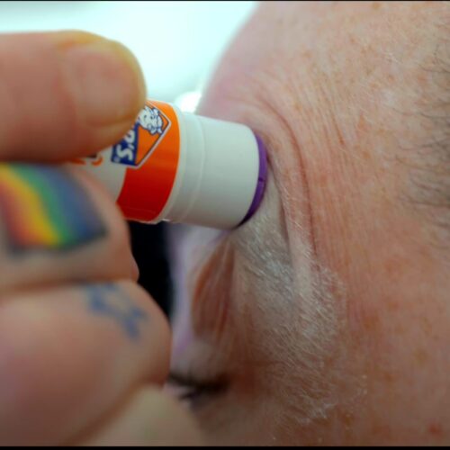 Een drag queen tijdens een make-over transformatie, met professionele make-up en styling die de artistieke expressie en transformatie laat zien