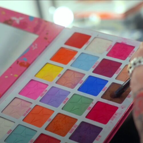 Een drag queen tijdens een make-over transformatie, met professionele make-up en styling die de artistieke expressie en transformatie laat zien