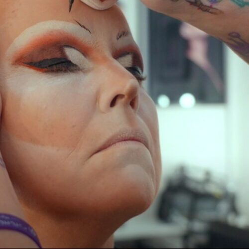 Een drag queen tijdens een make-over transformatie, met professionele make-up en styling die de artistieke expressie en transformatie laat zien