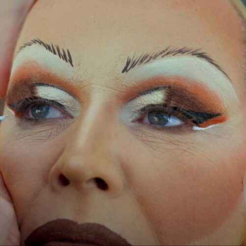 Een drag queen tijdens een make-over transformatie, met professionele make-up en styling die de artistieke expressie en transformatie laat zien