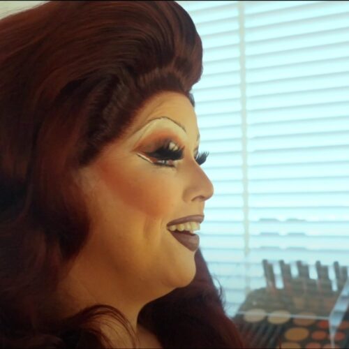 Een drag queen tijdens een make-over transformatie, met professionele make-up en styling die de artistieke expressie en transformatie laat zien